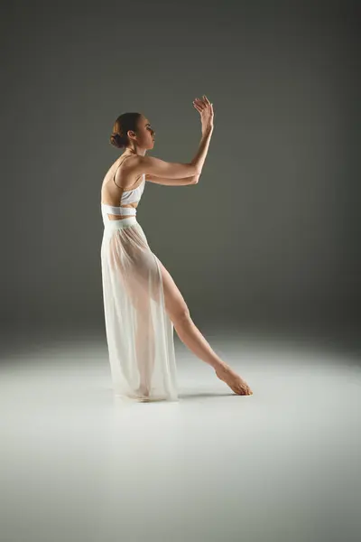Young ballerina gracefully dances in a white dress. — Stock Photo