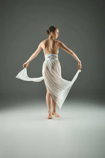 A young, beautiful ballerina dances gracefully in a flowing white dress. — Stock Photo