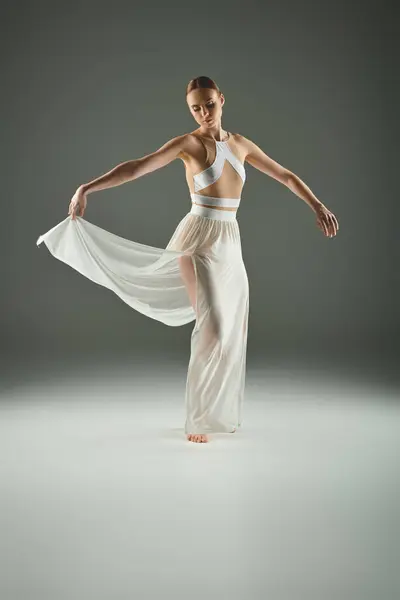 Young, beautiful ballerina in a white dress dancing gracefully on stage. — Stock Photo