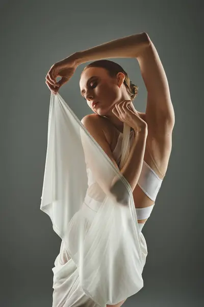 Eine junge schöne Ballerina posiert in einem fließenden weißen Kleid. — Stock Photo