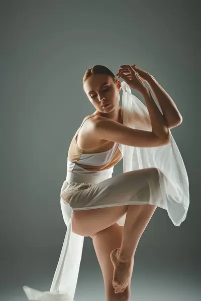 Une jeune, belle ballerine pose gracieusement dans une robe blanche. — Photo de stock