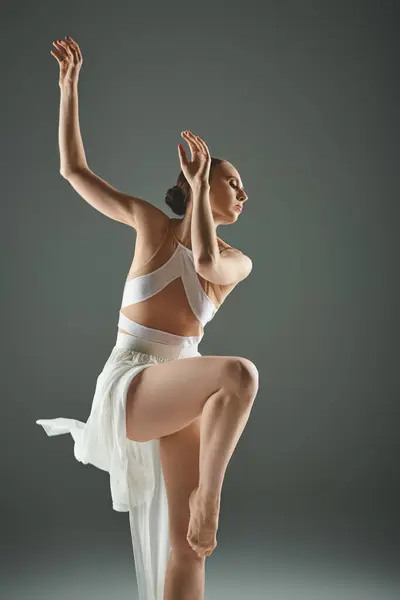 Una bailarina joven y hermosa en un vestido blanco baila con gracia. - foto de stock