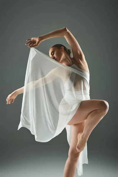 Молодая балерина в белом платье демонстрирует изящные танцевальные движения. — стоковое фото