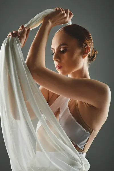 Una giovane, bella ballerina in un top bianco regge con grazia un panno bianco. — Foto stock