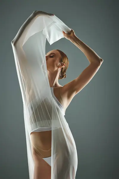 A young, beautiful ballerina in a sheer white dress poses gracefully for a picture. — Stock Photo