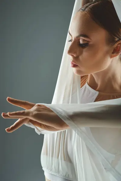 Una joven bailarina exhibe gracia y equilibrio en un vestido blanco, extendiendo sus manos con gracia. - foto de stock