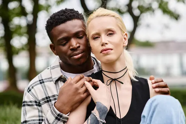 A happy multicultural couple - an African American man and a Caucasian woman - sitting side by side in a park. — Stock Photo