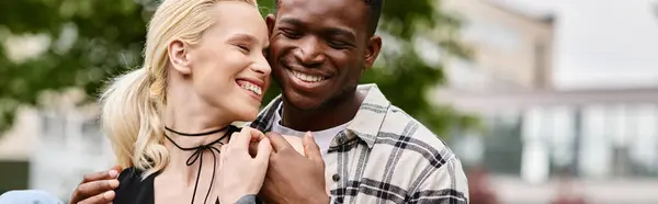 A happy multicultural couple, an African American man and a Caucasian woman, standing together in a park. — Stock Photo