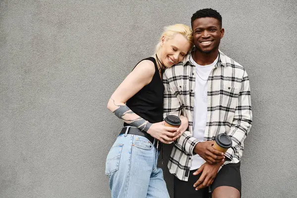 Ein fröhlicher multikultureller Freund und seine Freundin stehen Seite an Seite in der Nähe eines grauen Gebäudes an einer städtischen Straße. — Stockfoto