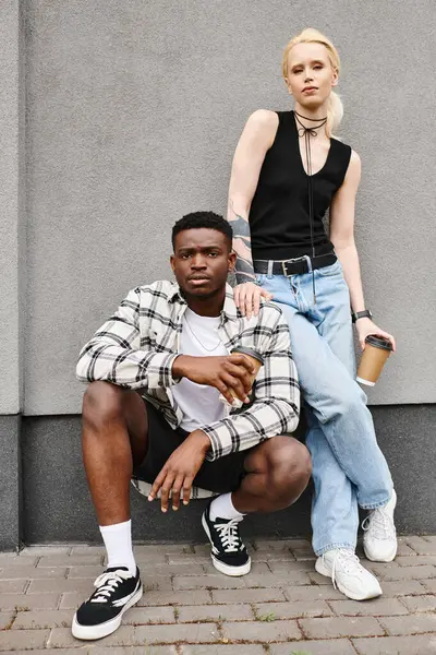 Ein glückliches Paar, ein Mann und eine Frau unterschiedlicher Herkunft, posieren gemeinsam auf einer städtischen Straße in der Nähe eines grauen Gebäudes. — Stockfoto