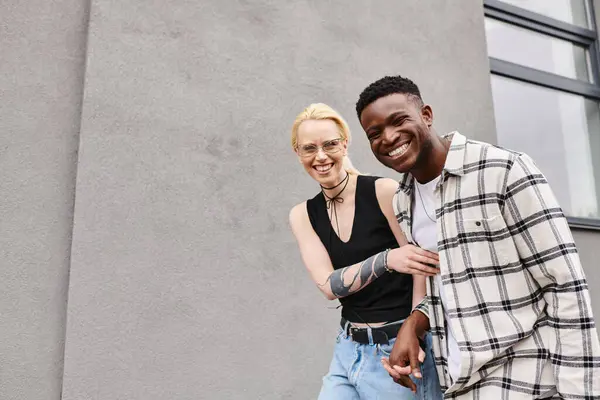 Multikulti-Freund und Freundin stehen glücklich zusammen auf einer städtischen Straße in der Nähe eines grauen Gebäudes. — Stockfoto