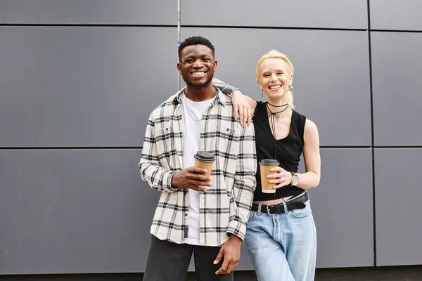 Ein multikulturelles Paar steht glücklich nebeneinander auf einer städtischen Straße in der Nähe eines grauen Gebäudes. — Stockfoto