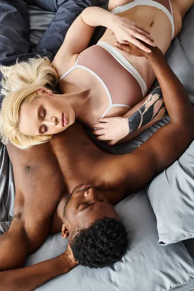 Ein stilvolles multikulturelles Paar, der Mann und die Frau, die friedlich auf dem Bett liegen. — Stockfoto