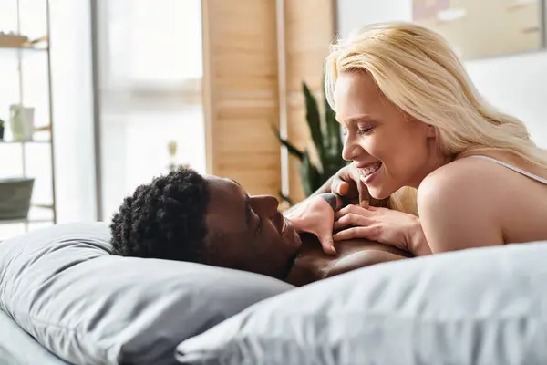A sexy, multicultural couple cuddling and relaxing in bed at home. — Stock Photo