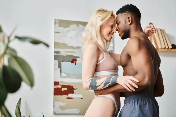 A man and a woman, of different ethnic backgrounds, stand in lingerie, exuding sensuality and intimacy at home. — Stock Photo
