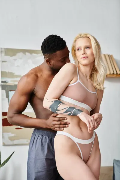 Uomo e donna multiculturali vestiti in lingerie condividono un momento intimo mentre posano per una foto seducente. — Foto stock