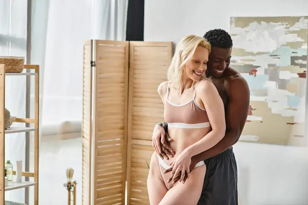 A multicultural couple, exuding sensuality, in lingerie, intimate in a bedroom setting. — Stock Photo
