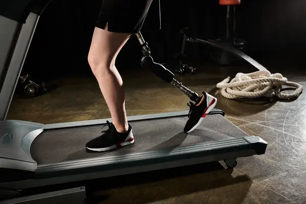 A person with a prosthetic leg is walking on a treadmill in a gym, showing determination and strength in their workout routine. - foto de stock