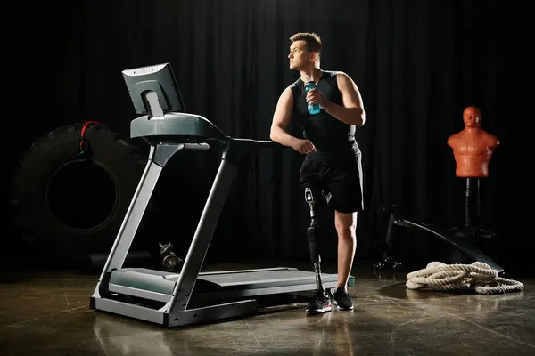 A determined disabled man with a prosthetic leg stands confidently on top of a treadmill at the gym. — Stock Photo