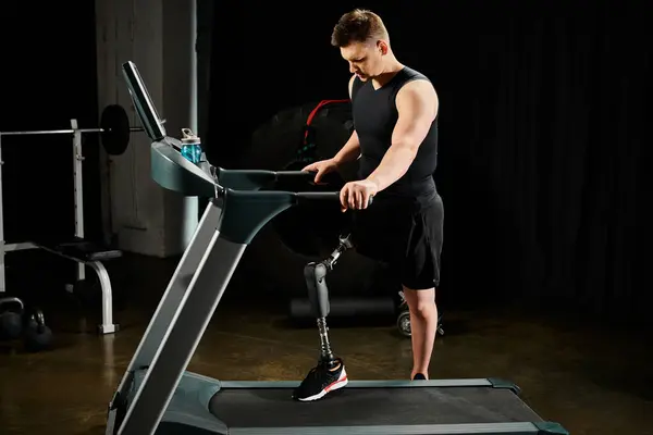 Ein behinderter Mann mit Beinprothese benutzt in einem schwach beleuchteten Raum ein Laufband, um sich auf sein Training zu konzentrieren.. — Stockfoto