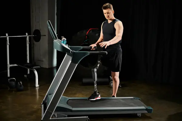 Un hombre con una pierna protésica se para en una cinta de correr en una habitación débilmente iluminada, mostrando determinación y resistencia. - foto de stock
