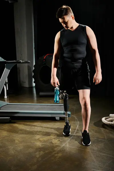 Un uomo con una gamba protesica si trova accanto a una macchina, concentrandosi sulla sua routine di allenamento in palestra.. — Foto stock