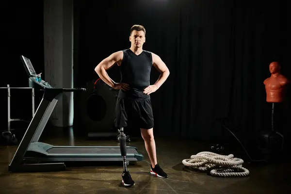 Un homme avec une prothèse de jambe se tient en confiance devant un tapis roulant, prêt à se mettre au défi dans la salle de gym. — Photo de stock