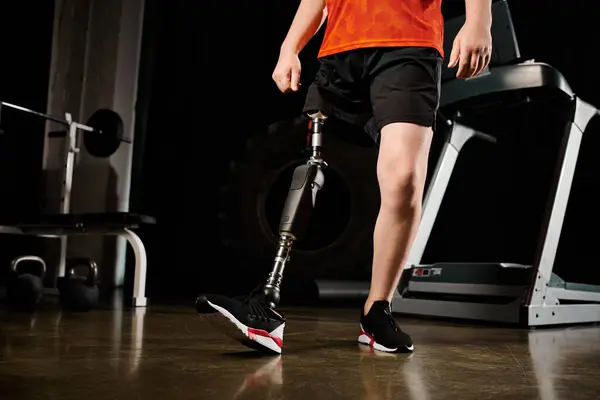 Un hombre discapacitado, con una pierna protésica, de pie en el gimnasio mientras hace ejercicio. - foto de stock