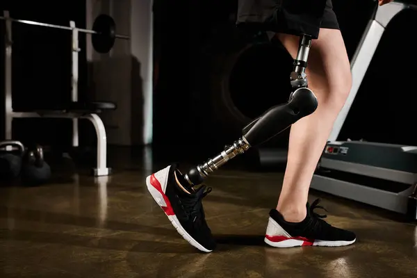 Una persona con una gamba protesica cammina su un tapis roulant in palestra, mostrando determinazione e forza nella loro routine di allenamento.. — Foto stock
