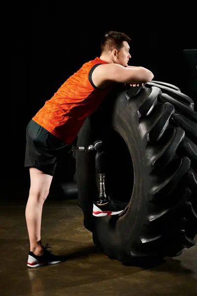 Ein Mann mit Beinprothese steht neben einem massiven Reifen, bereit für eine herausfordernde Trainingsroutine. — Stockfoto