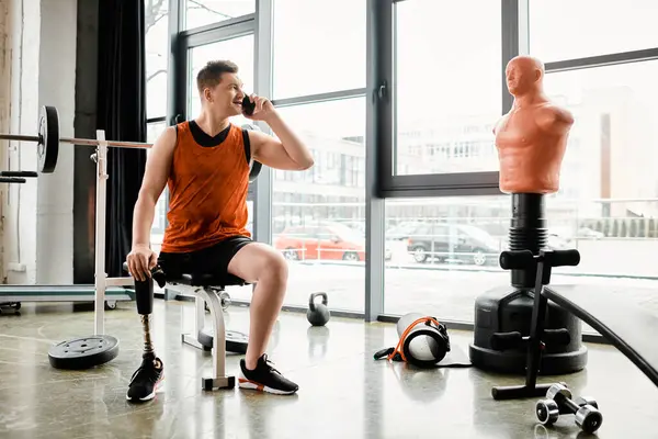 Ein Mann mit Beinprothese sitzt auf einem Stuhl und unterhält sich auf seinem Handy. — Stockfoto