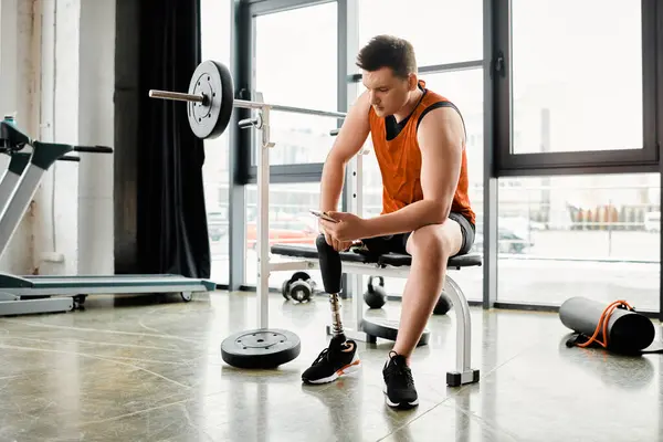Un uomo con una gamba protesica siede su una panchina, assorbito nel suo cellulare. — Foto stock