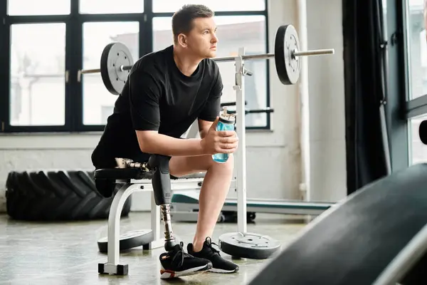 Un uomo con una gamba protesica, si siede su una panchina, tenendo casualmente una bottiglia d'acqua. — Foto stock