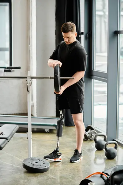 Un hombre discapacitado con una pierna protésica trabajando en una máquina en un gimnasio. - foto de stock
