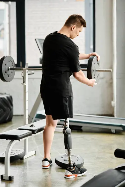 Un homme avec une prothèse de jambe à l'aide d'une machine au gymnase pour renforcer et améliorer la mobilité. — Photo de stock