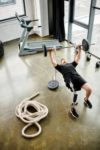 Un uomo disabile con una gamba protesica esegue un deadlift in una palestra, mostrando forza, determinazione e resilienza. — Foto stock