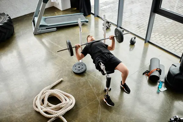 Un homme avec une prothèse de jambe s'engage dans un puissant soulèvement dans une salle de gym, montrant force et détermination. — Photo de stock