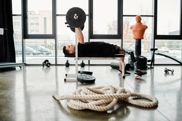 Людина з інвалідністю з протезною ногою лежить на лавці, обличчям до мотузки перед ним, у визначеному тренуванні. — стокове фото