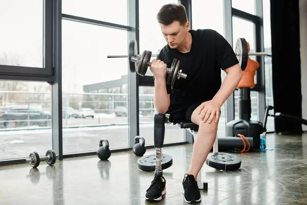 A determined man with a prosthetic leg performs a squat while holding a dumbbell in a gym. — Stock Photo