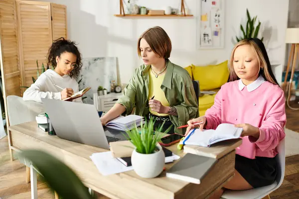 Three interracial teenage girls engaged in focused study sitting at a table with laptops. — Stock Photo