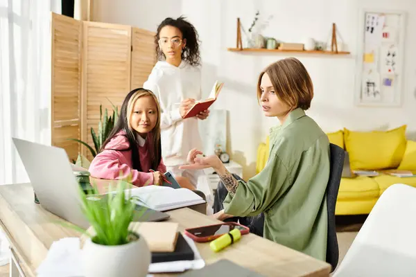 A tight-knit group of multiracial teenage girls sitting at a table, engrossed in their laptops while studying and supporting each other. — Stock Photo