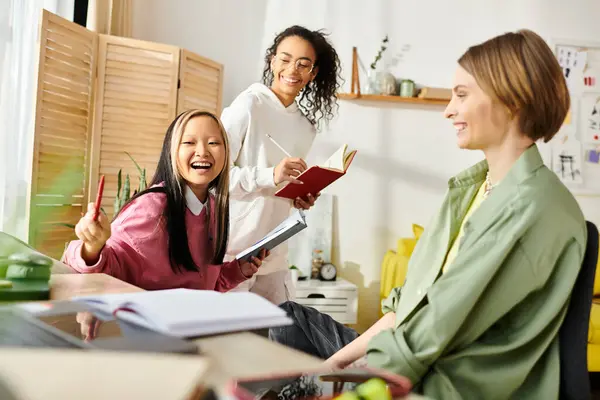 A diverse group of teenage girls of different races sitting around a table with books, studying and engaging in lively discussions. — Stock Photo