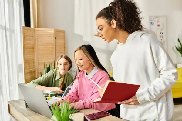 Teenage friends from different backgrounds sit around a table, engrossed in their laptops, studying and learning together. — Stock Photo