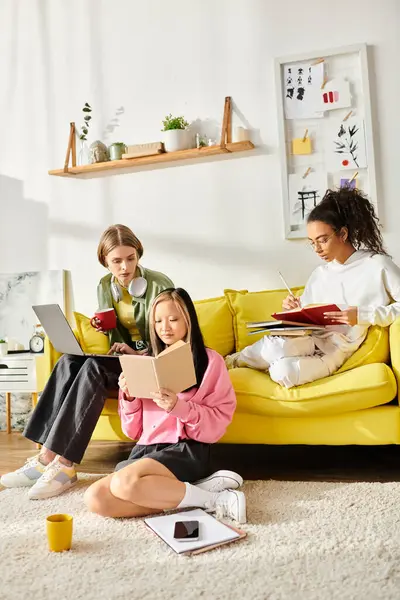 A diverse group of teenage girls sitting on top of a yellow couch, deep in study and friendship. — Stock Photo