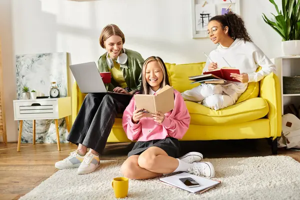 A diverse group of teenage girls sit closely together on a vibrant yellow couch, engrossed in studying and deep in conversation. — Stock Photo