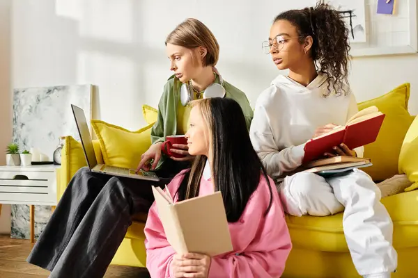 Three teenage girls of different races sit on a couch, absorbed in books, creating a scene of unity and shared knowledge. — Stock Photo