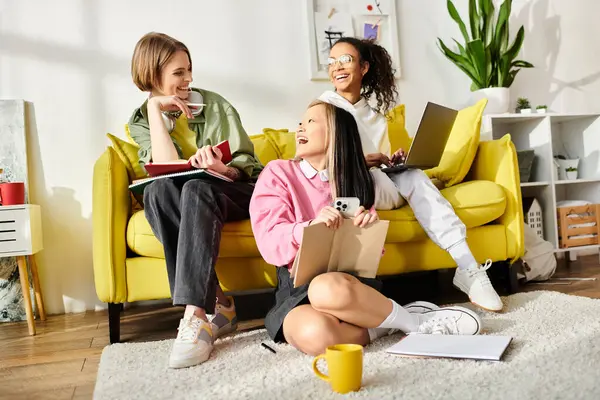 Un grupo diverso de adolescentes se reúnen en un vibrante sofá amarillo para estudiar, reír y apoyarse mutuamente en un ambiente cálido y acogedor.. - foto de stock