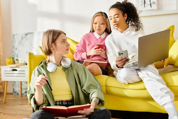 A group of diverse teenage girls in casual attire engaging in conversation while seated on a vibrant yellow couch. — Stock Photo