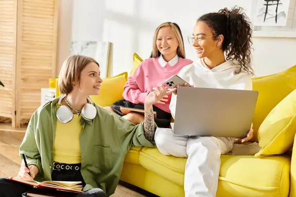 A diverse group of teenage girls engaging in a study session on a vibrant yellow couch. — Stock Photo