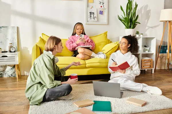 Un grupo diverso de adolescentes estudian y se unen en un acogedor sofá amarillo, fomentando la amistad y el crecimiento educativo. - foto de stock